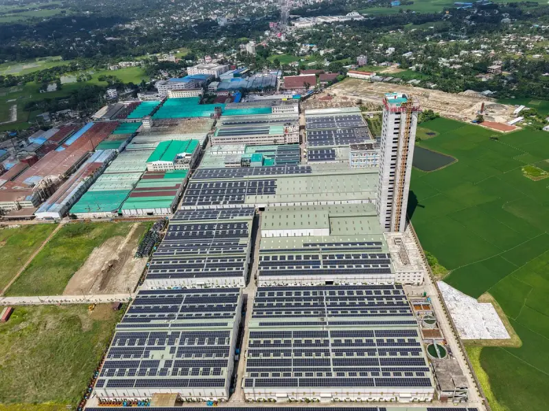 Aerial view of a sprawling industrial complex with solar panels and green fields around it
