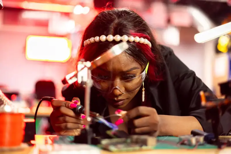 A woman engineer solders electronic equipment with precision tools at a workbench