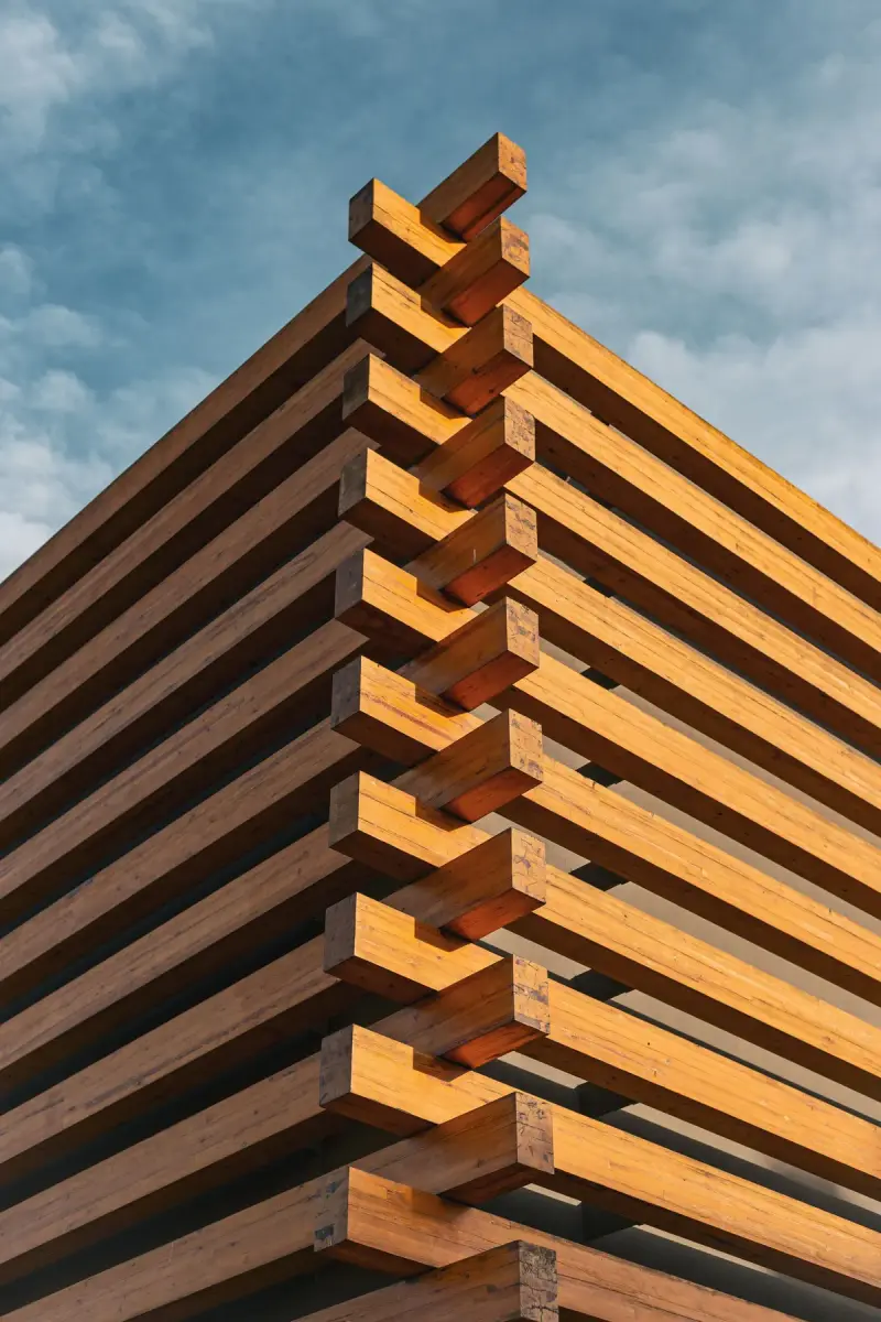 Symmetrical wooden lattice structure seen from below against a blue sky