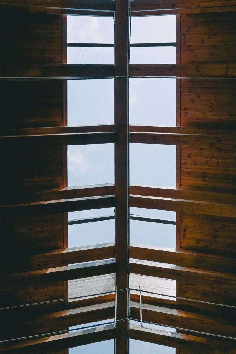 Wooden roof structure with open skylights letting daylight through