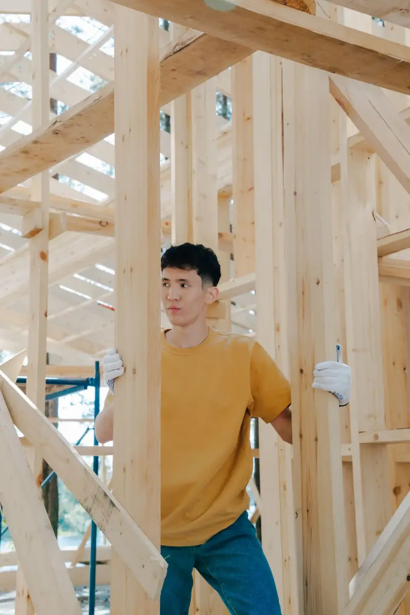 Young worker examining wooden beams on a building site