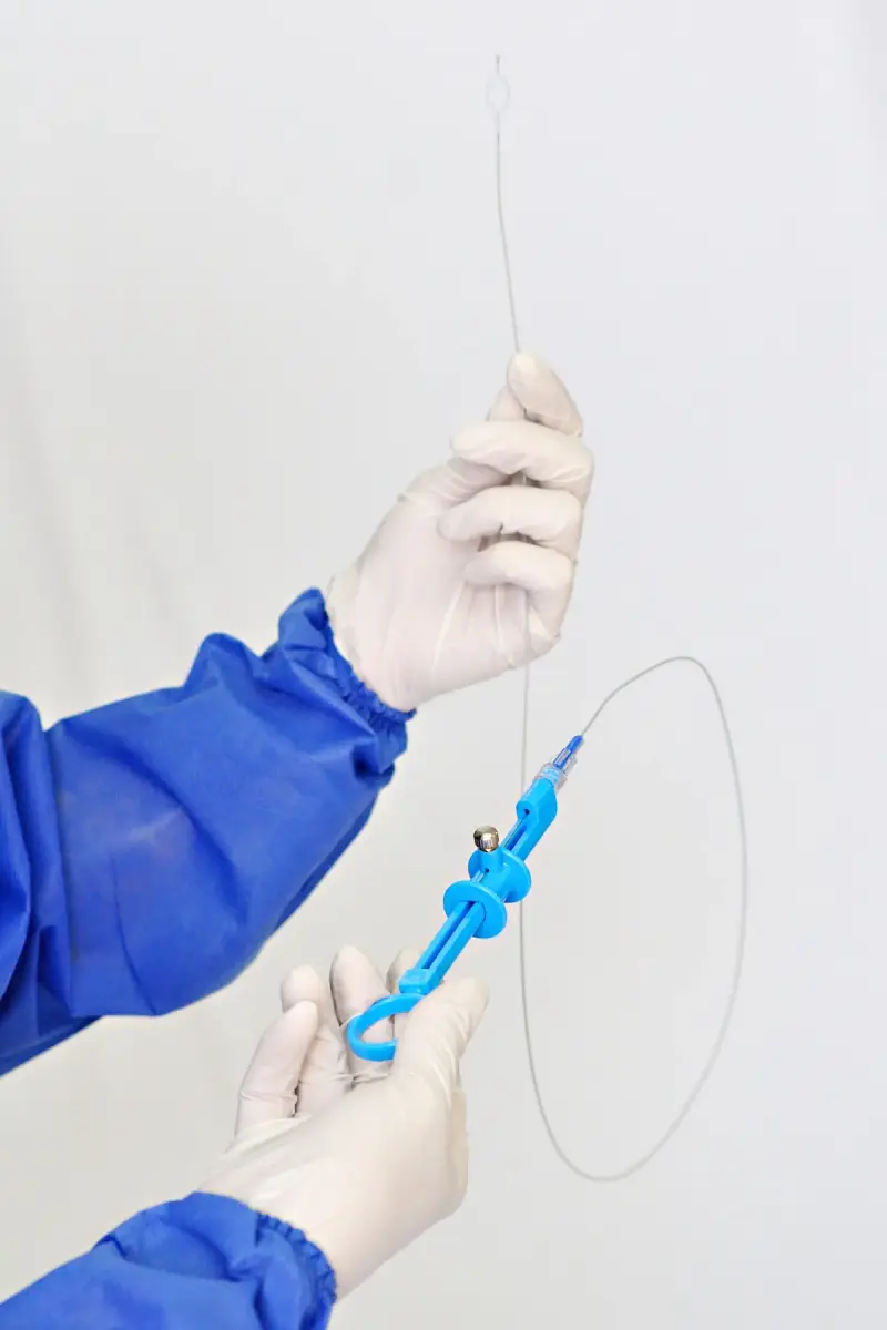 Close view of a medical professional's gloved hands holding and demonstrating a catheter