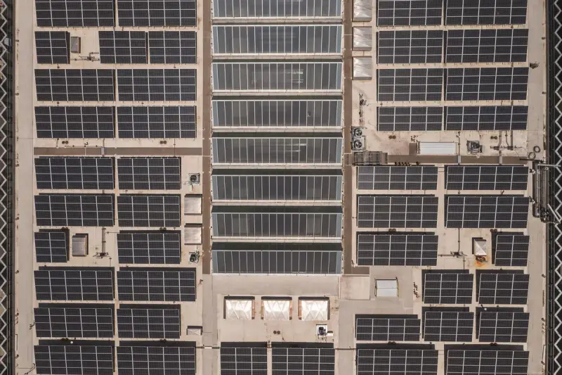 Drone view of a grid of solar panels across a large commercial rooftop