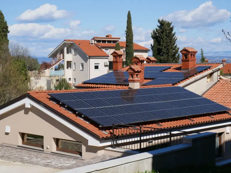 Neighborhood of red tile roofs fitted with solar panels in sunshine
