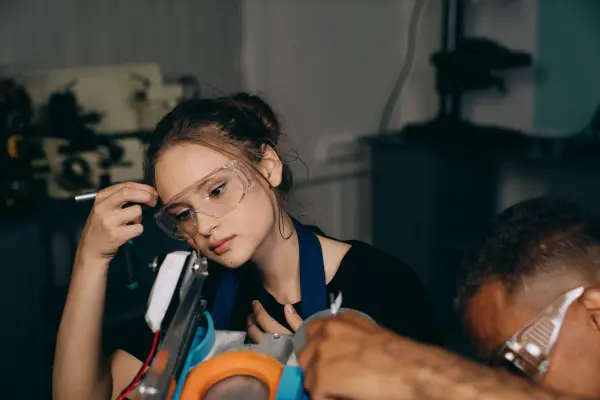 Woman wearing protective goggles working with equipment in an industrial workshop