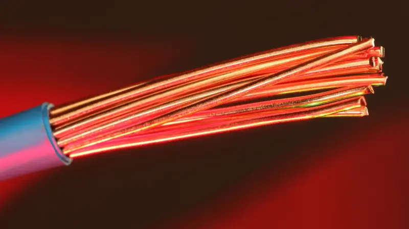 Fine copper wires illuminated with red light against a dark background