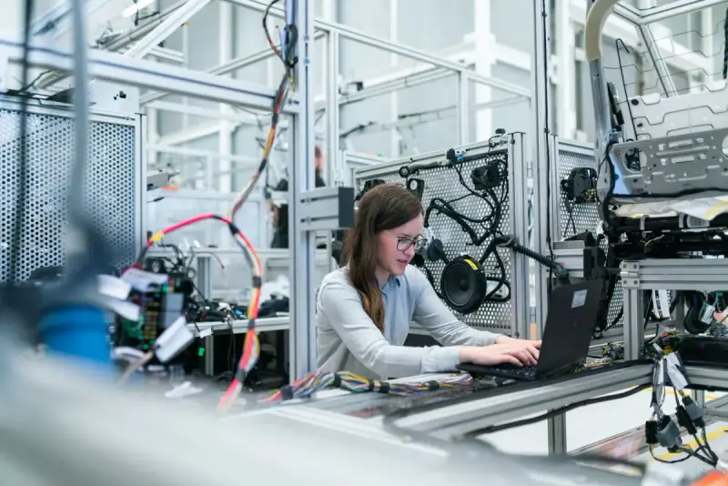 Female engineer working on a laptop beside technical equipment in a laboratory