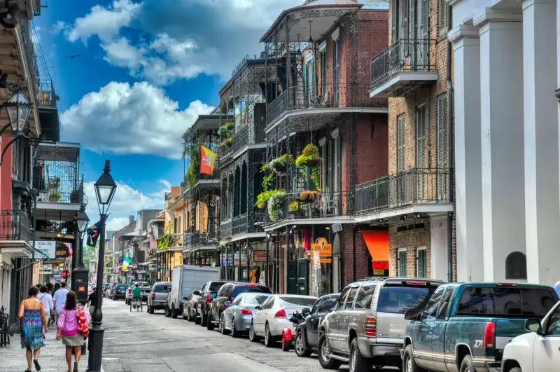 Visitors walking a French Quarter street lined with historic balconied buildings in New Orleans
