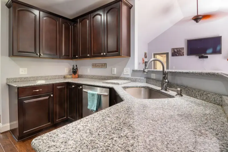 Kitchen with a long granite countertop, undermount sink and dark wood cabinets