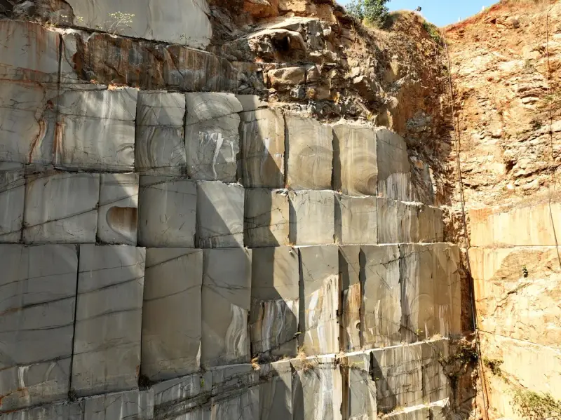 Sunlit granite quarry wall cut into large blocks