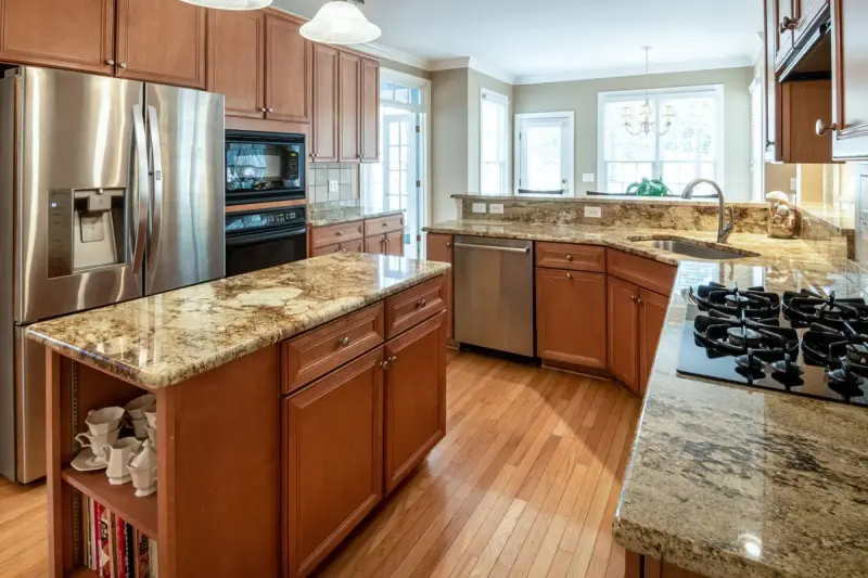 Kitchen with a granite island and counters, wood cabinets and steel appliances