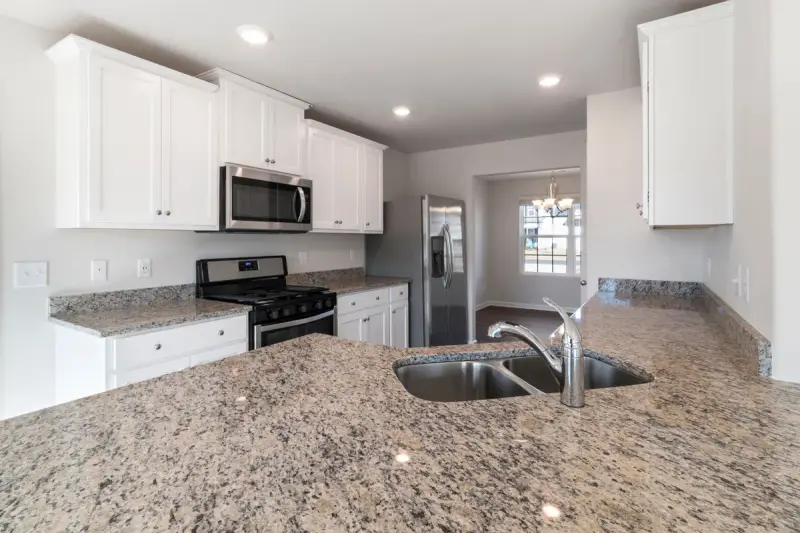 White kitchen with a granite counter, double sink and gas range