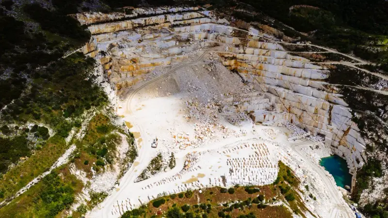 Aerial view of a white marble quarry surrounded by green hills