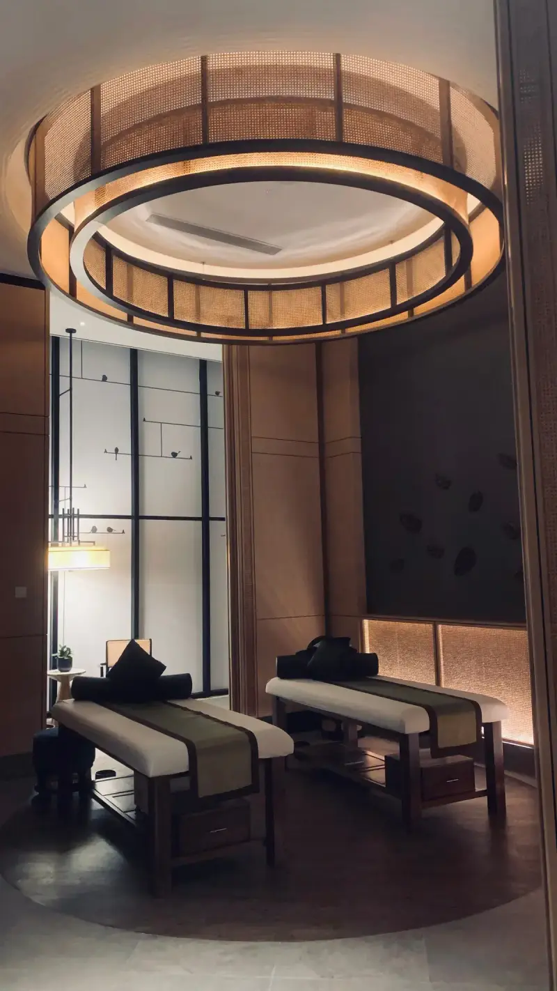 Couples spa treatment room with two beds under a round pendant light