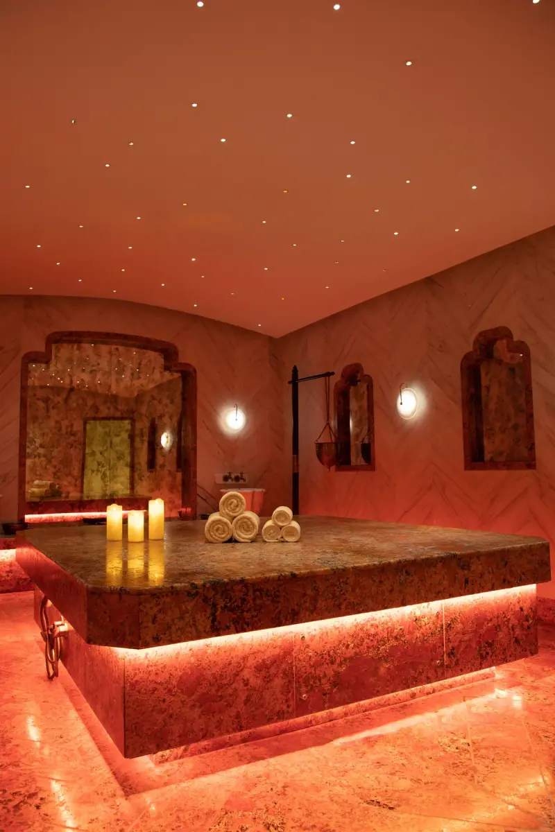Candlelit hammam with a heated marble platform and rolled towels