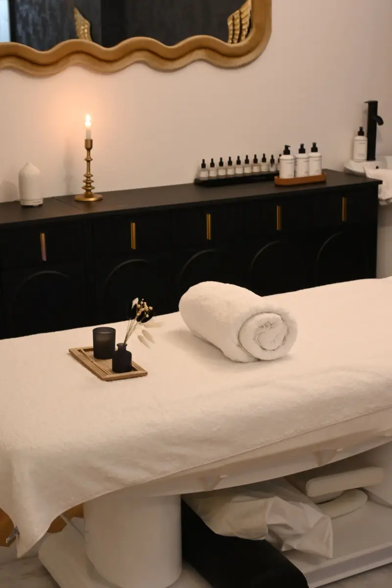 Spa treatment table with a rolled towel, candle and amber oil bottles