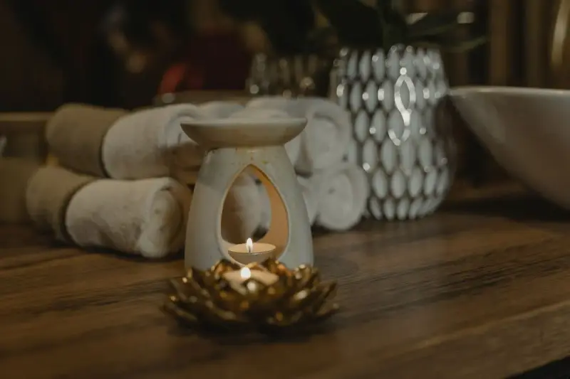 Lit candle in a ceramic holder beside plush folded towels