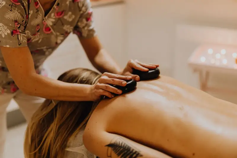 Massage therapist placing warm stones during a spa treatment