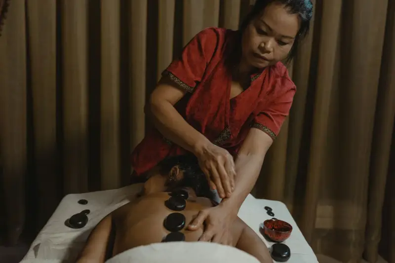 Therapist giving a relaxing hot stone massage indoors