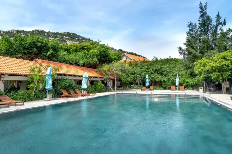Resort pool with loungers and umbrellas surrounded by greenery