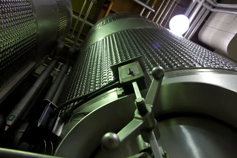 Low-angle view of large dimpled stainless steel vessels inside an industrial plant
