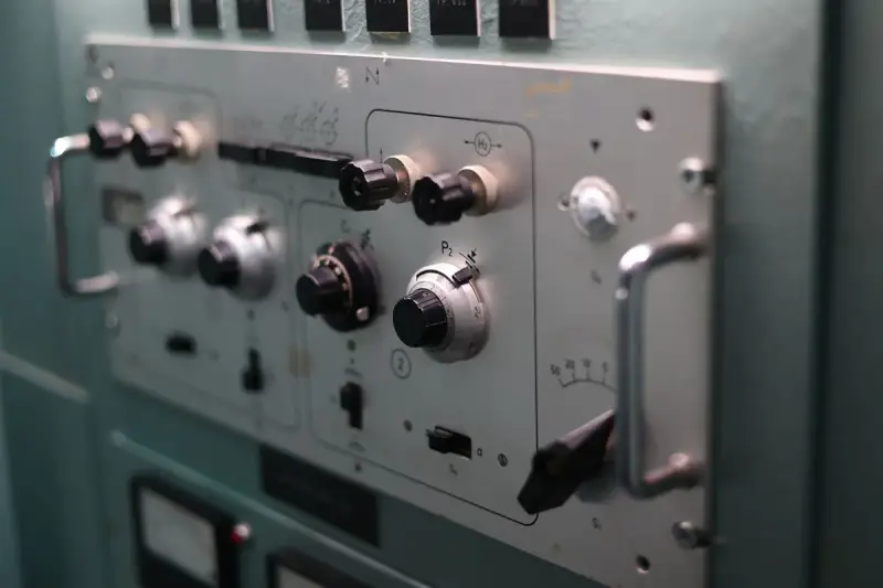 Switches, dials and handles on a grey industrial control panel