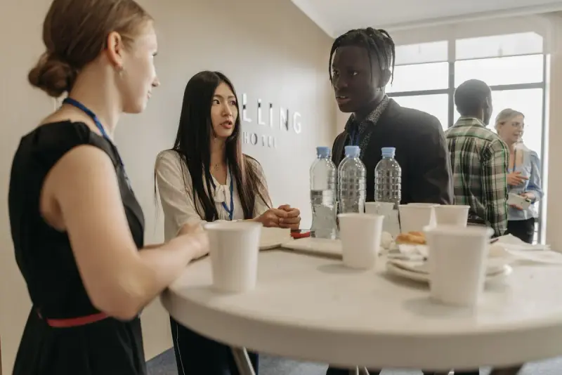 Conference attendees with badges talking over coffee at a high table