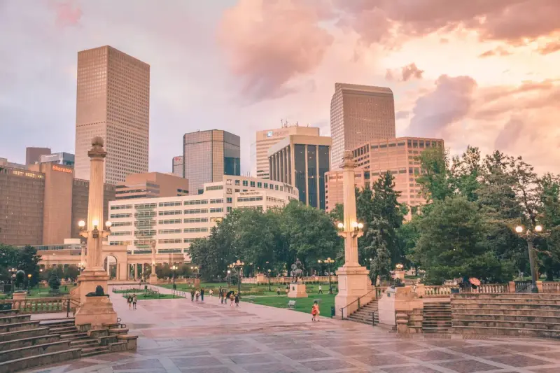 People in a city park with the Denver skyline behind at sunset
