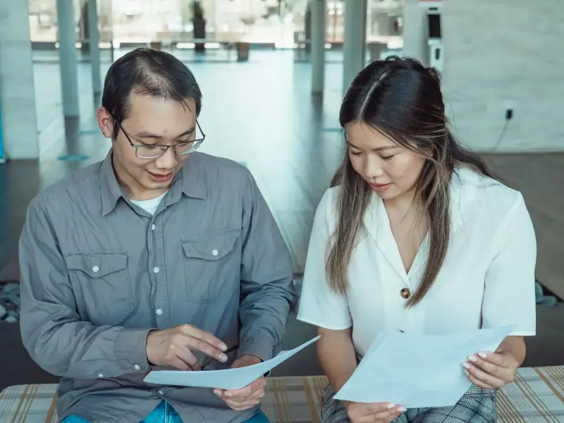 Two coworkers reviewing documents together in a modern office