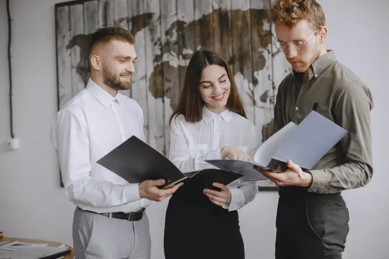 Three young professionals reviewing documents together with smiles