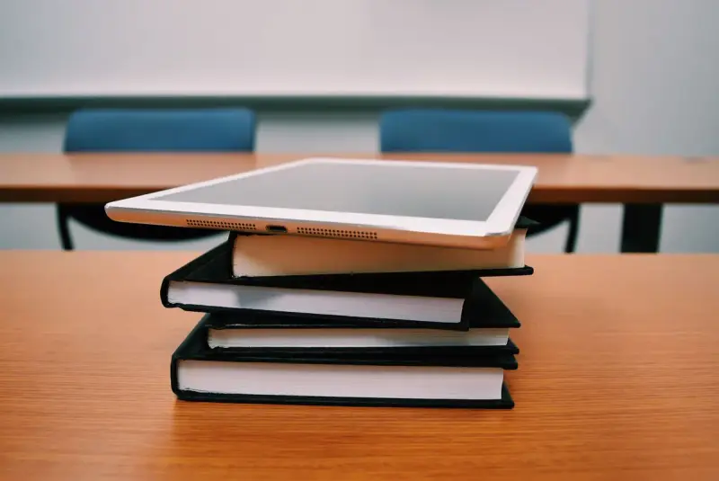 Silver tablet resting on a stack of books in an empty classroom