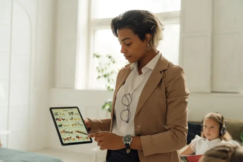 Teacher using a tablet to explain a lesson in a bright classroom