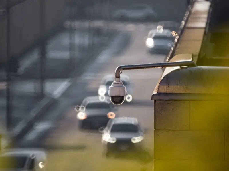 Roadside camera monitoring a busy road with blurred vehicles behind it