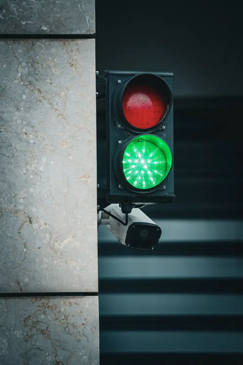 Traffic signal showing green with a camera mounted nearby on a city street