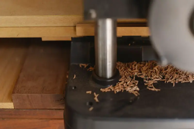 Shaper spindle on a woodworking machine surrounded by fresh wood shavings