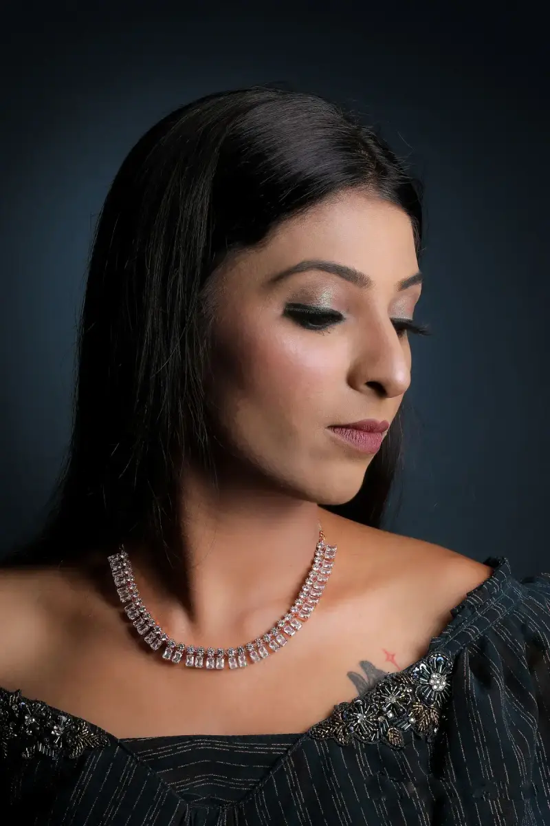Studio portrait of a woman in a dark sweater wearing a diamond tennis-style necklace