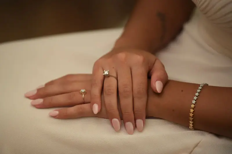 Manicured hands wearing stacked diamond rings and a gold bracelet