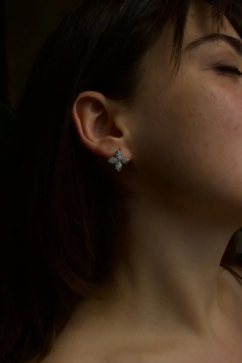 Profile of a woman wearing a small diamond cluster earring against a dark background
