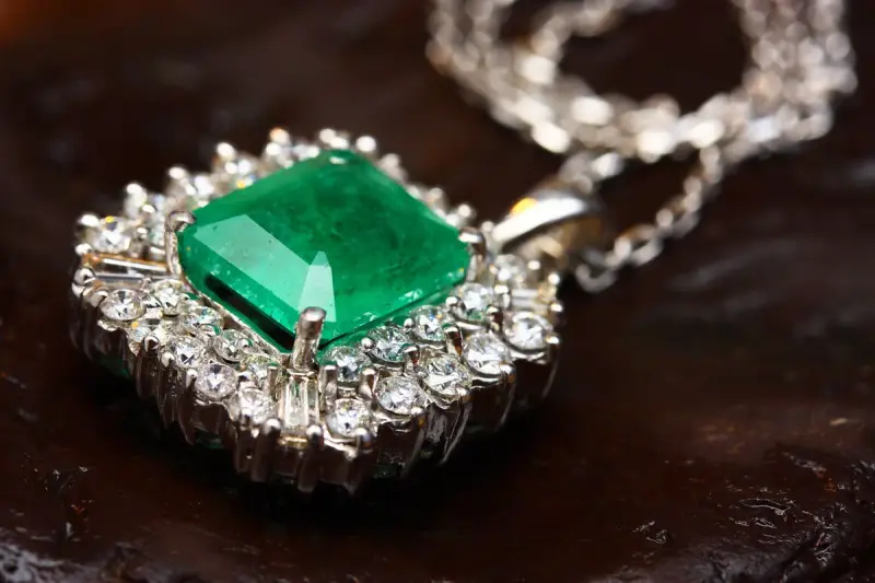 Emerald pendant in white gold surrounded by small diamonds