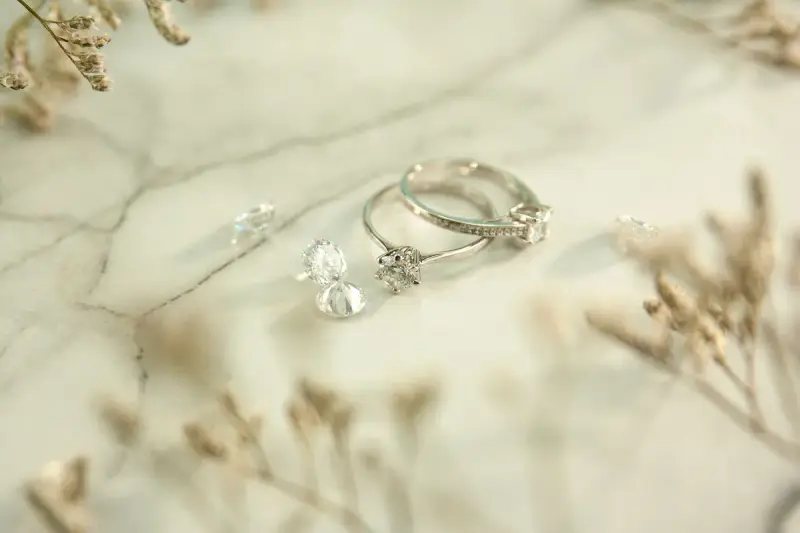 Silver rings and loose diamonds arranged on a marble table
