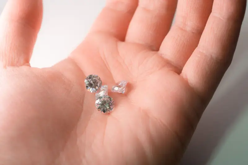 Several loose diamonds resting in the palm of a hand