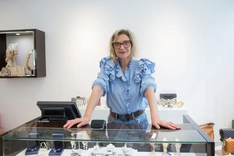Woman standing at a jewelry store counter lined with display cases