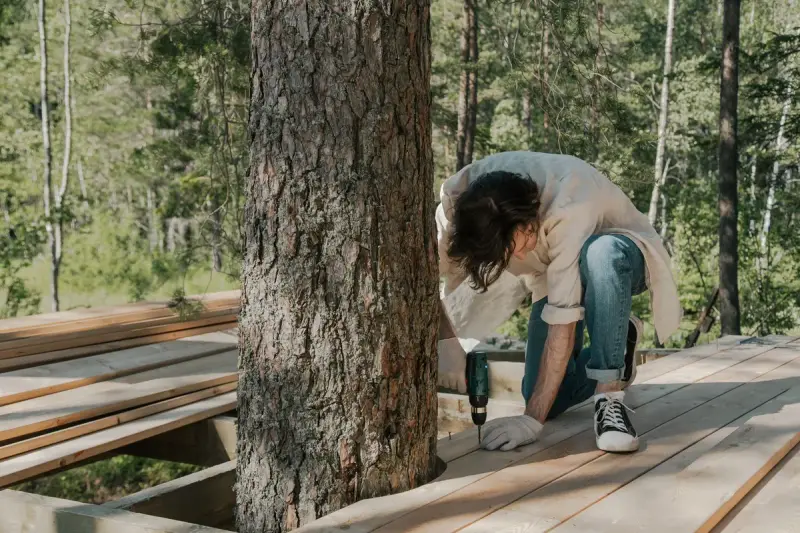 Worker driving screws into a wooden boardwalk with a cordless drill