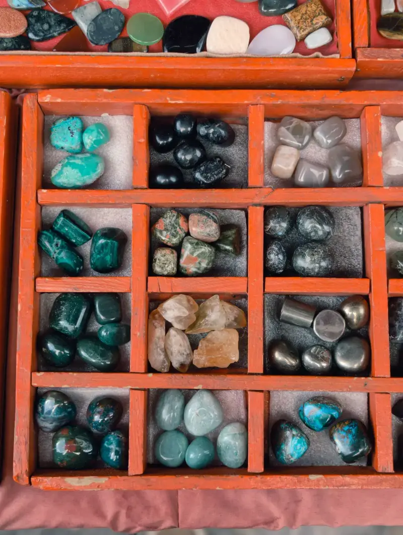 Polished turquoise, malachite and quartz stones sorted in a red wooden display box
