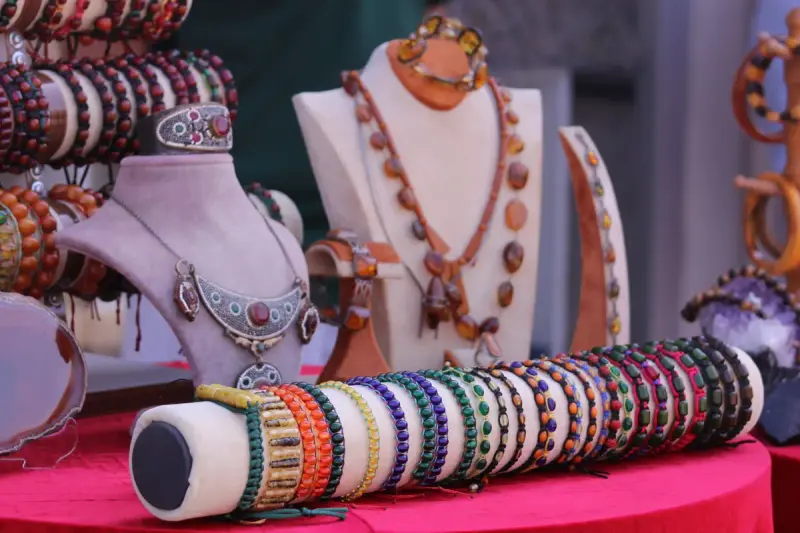 Handmade necklaces on busts and beaded bracelets on a roll in a vendor showcase
