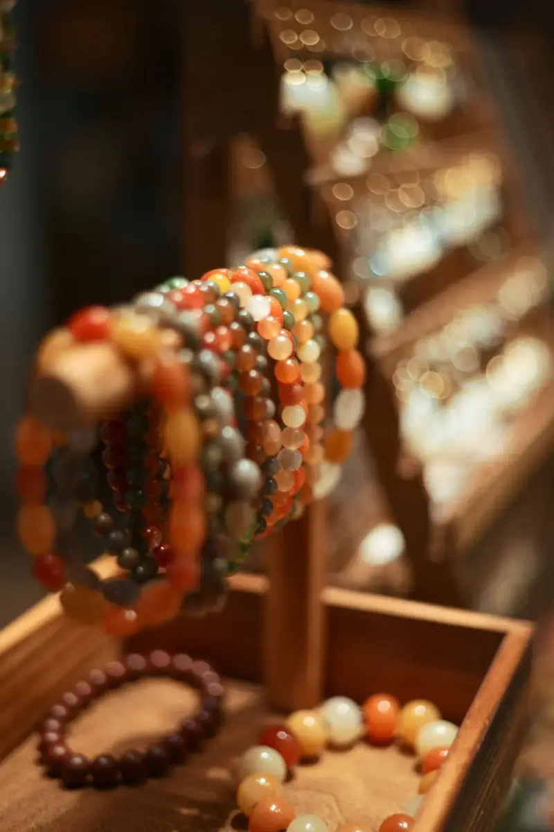 Gemstone bead bracelets stacked on a wooden display stand in warm light