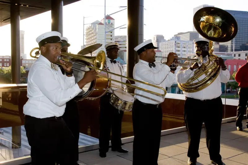 Brass band with trombone, trumpet, drums and sousaphone playing on a terrace above downtown New Orleans
