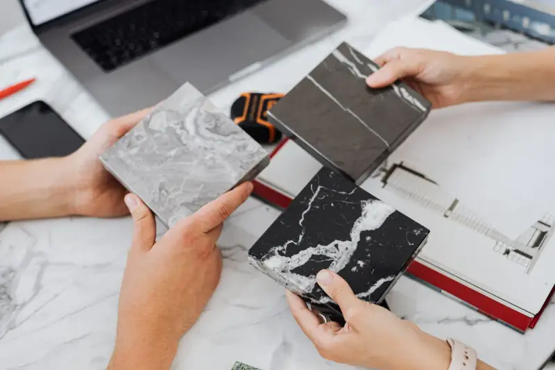 Two designers comparing marble and stone samples over drawings