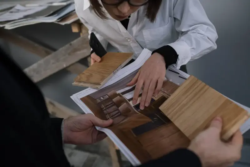 Designer holding wood samples against a printed room design