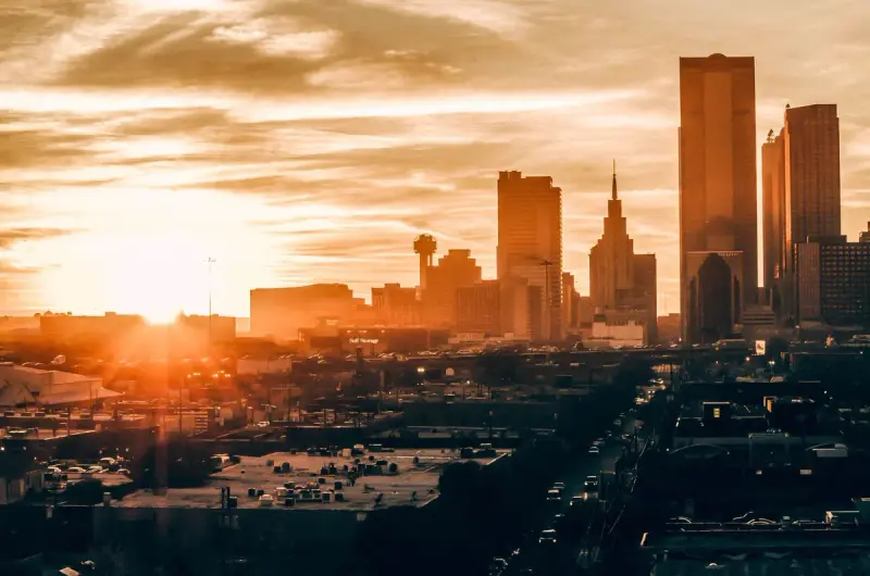 Dallas skyline silhouetted against an orange sunset sky